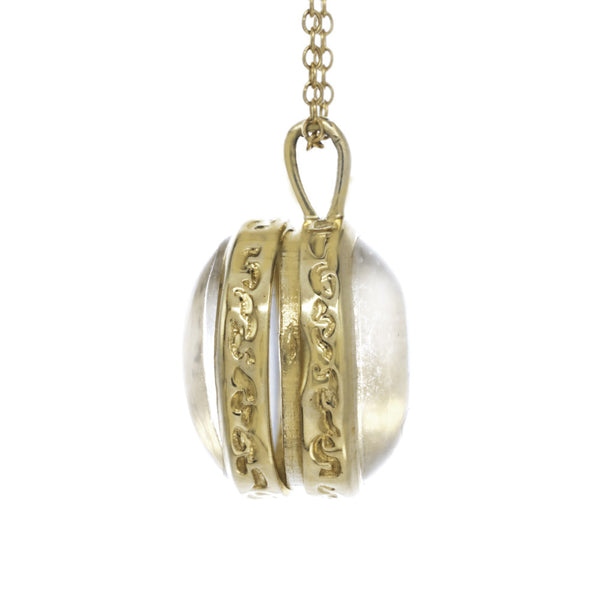 Gold locket with a Herkimer crystal on a gold chain side view.